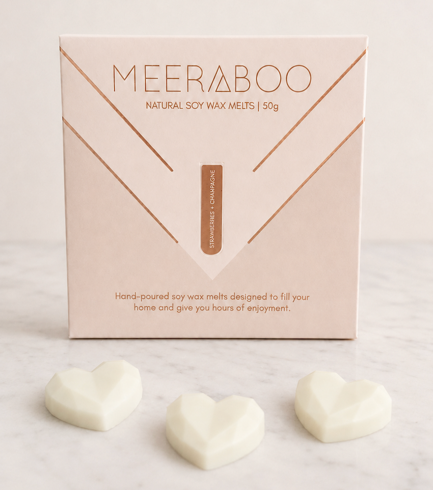 A box of MEERABOO Natural Soy Wax Meltsdisplayed on a white marble background with three white heart-shaped wax melts placed below the box.