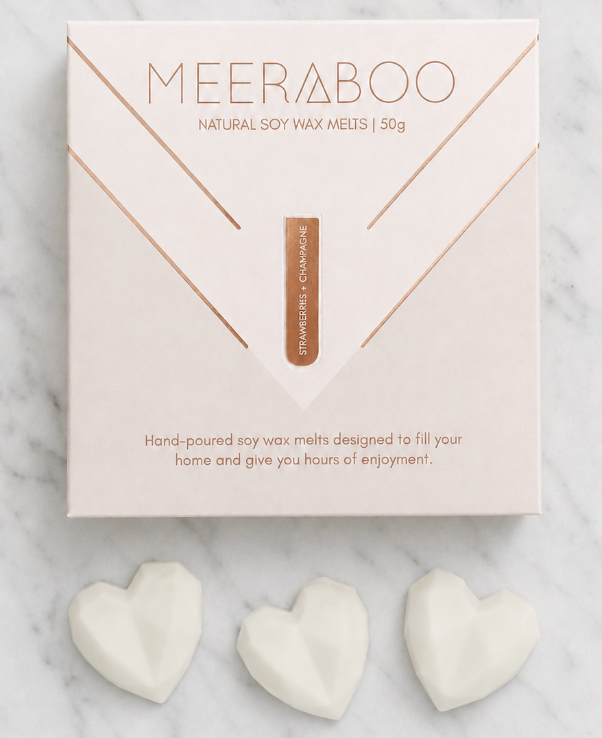 A box of MEERABOO Natural Soy Wax Meltsdisplayed on a white marble background with three white heart-shaped wax melts placed below the box.
