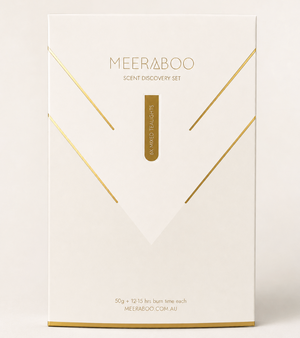 A clean, minimalist white box for the Meeraboo Scent Discovery Set 'Vibrant Touch' with elegant gold foil geometric lines and text, photographed on a warm off-white background.